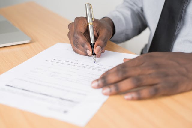 person signing a lease contract with a silver pen